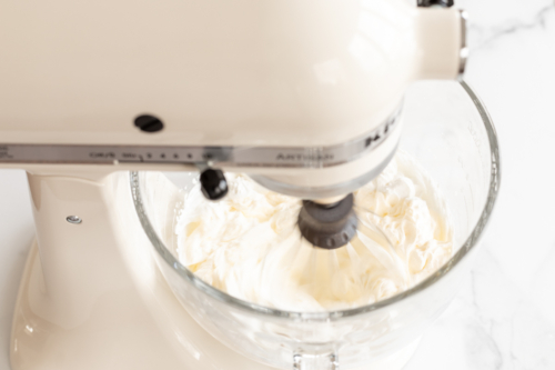 Cake batter ice cream ingredients in a glass bowl of a stand mixer.