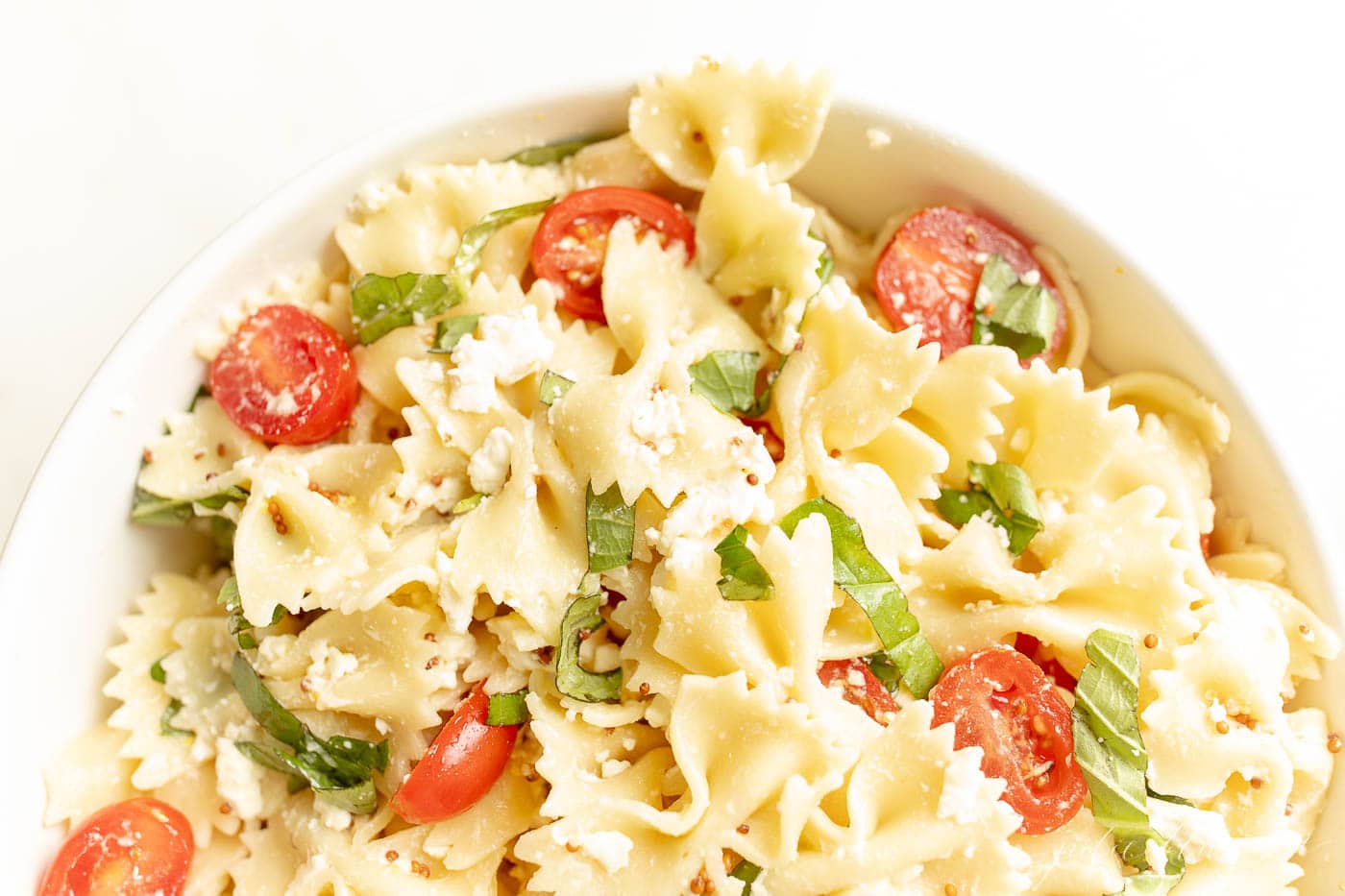 easy pasta salad recipe in a bowl with tomato and basil