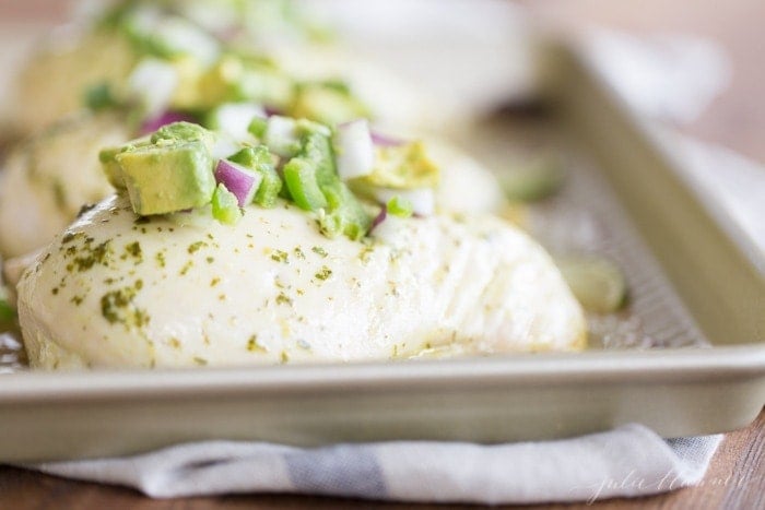 chunky avocado salsa on top of chicken breasts on baking sheet