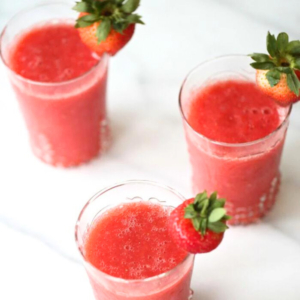 Three champagne slushies garnished with fresh strawberries