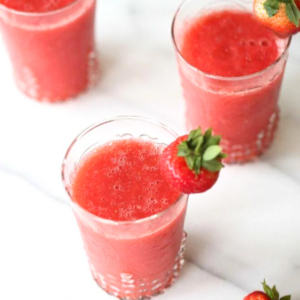 Three champagne slushies garnished with fresh strawberries