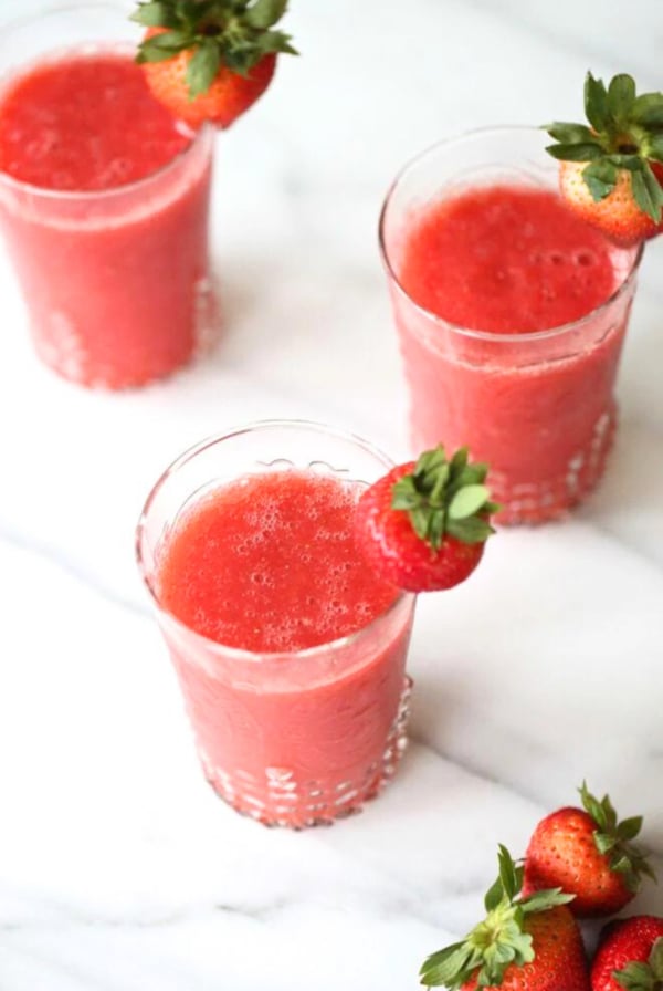 Three champagne slushies garnished with fresh strawberries