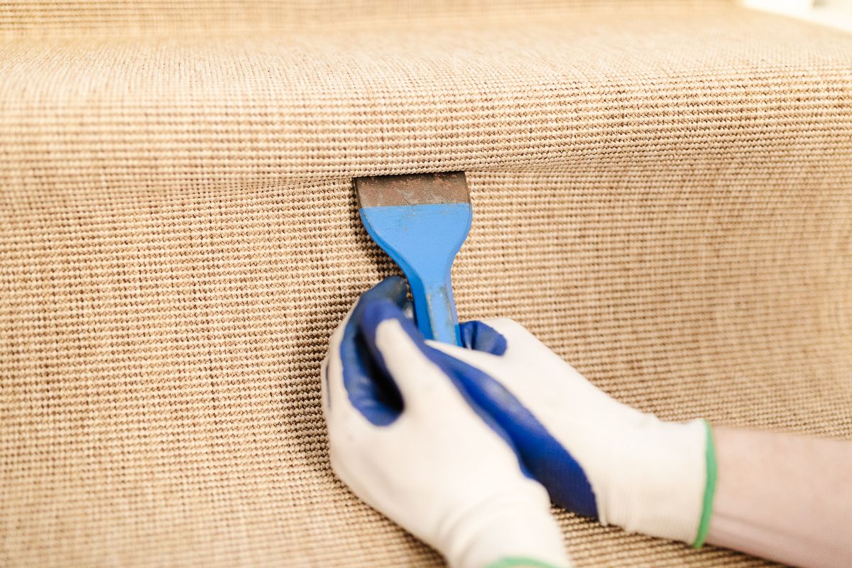 diy staircase makeover, gloved hands holding a carpet tucking tool against a modern stair runner