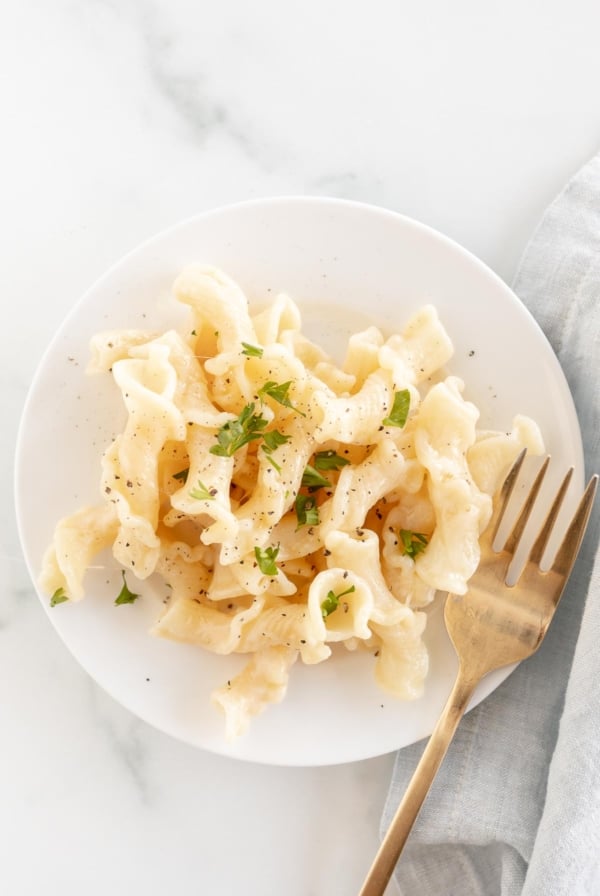 fontina cheese pasta on white plate with gold fork