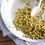 green peas in a skillet with wood spoon