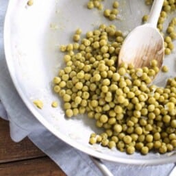 green peas in a skillet with wood spoon