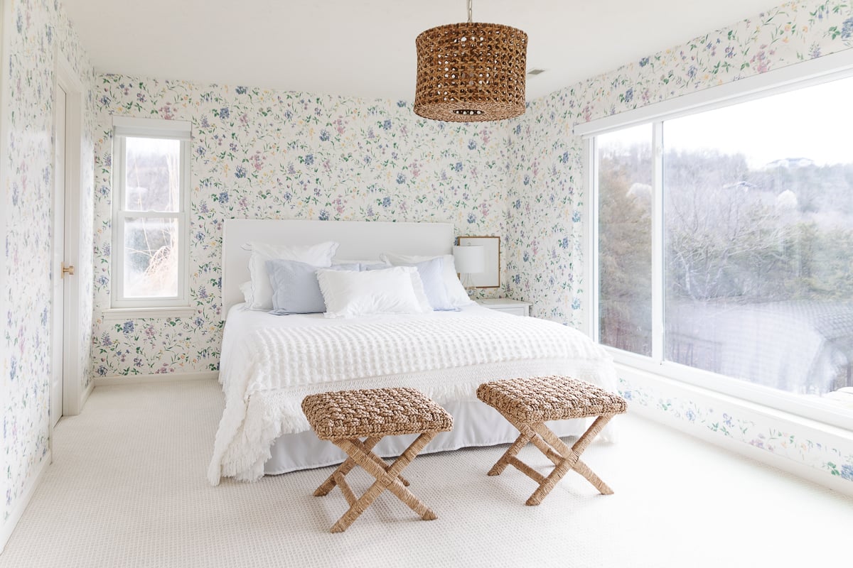 A bedroom with dated floral wallpaper and a bed.