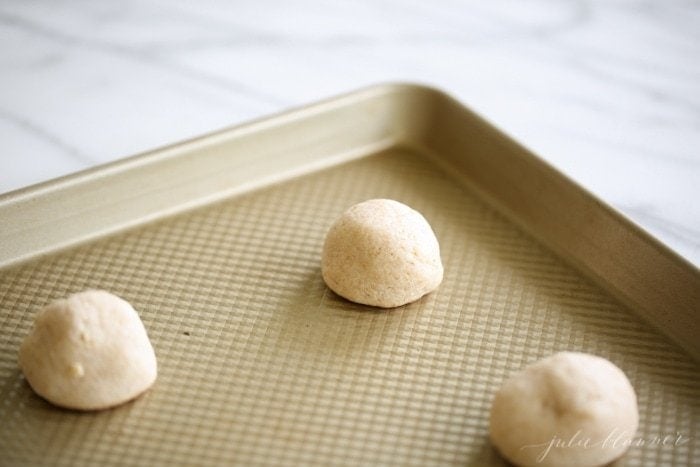 Pre-baked caramel cheesecake cookies on a baking tray.