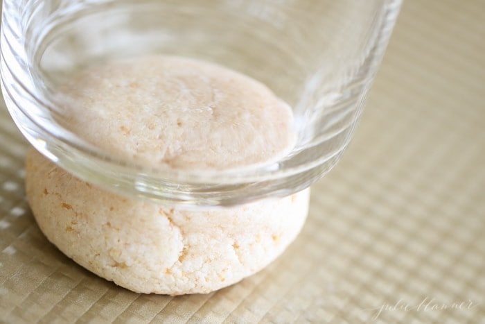 Salted caramel cheesecake cookies being smashed with the bottom of a cup.