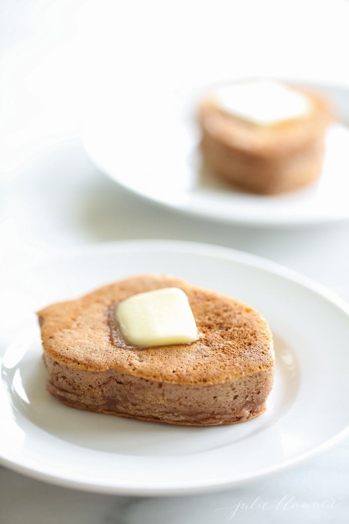 Two chocolate protein pancakes served on white plates