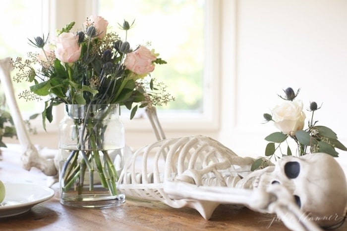 A skeleton on a dining table with fresh flowers