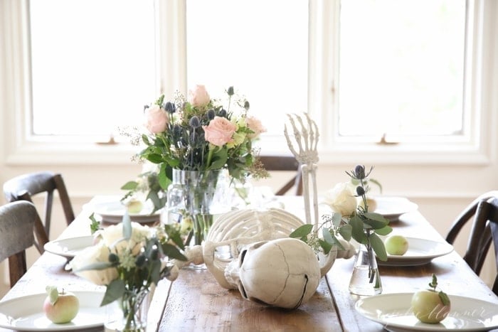 A skeleton on a dining table with fresh flowers