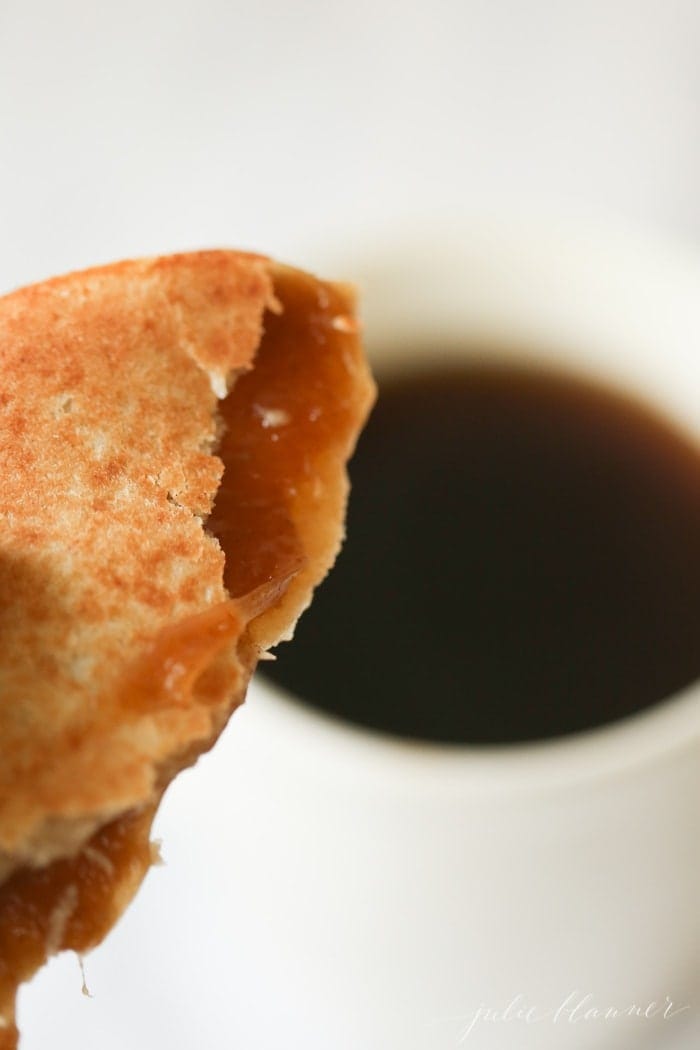 a stroopwafel with bites taken out, cup of coffee in the background