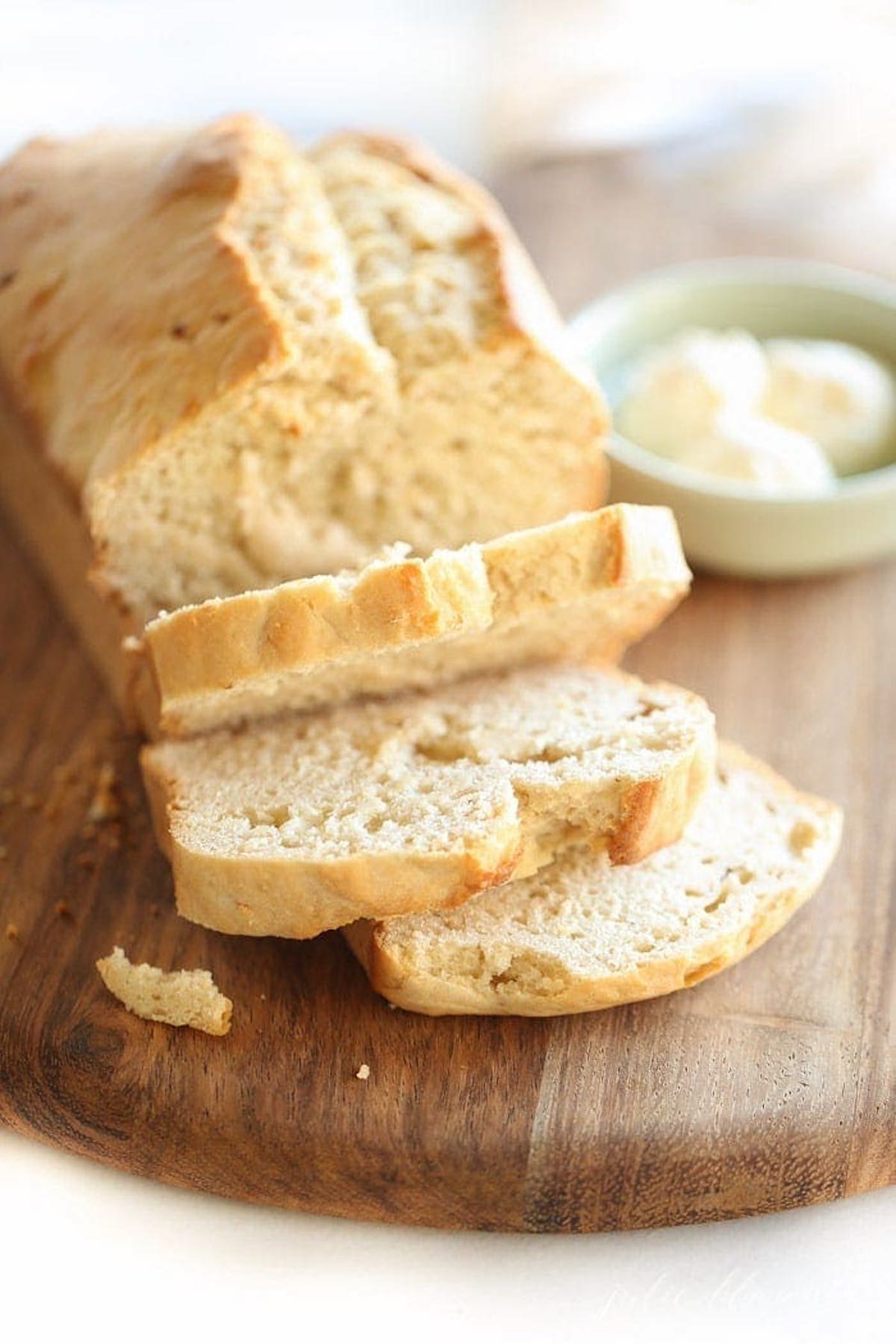 A loaf of honey beer bread with butter on a cutting board.