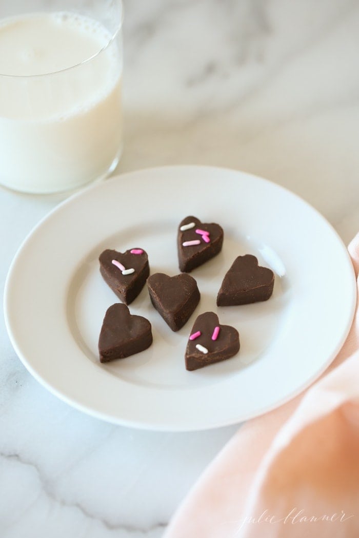 Fudge on a white plate next to a glass of milk