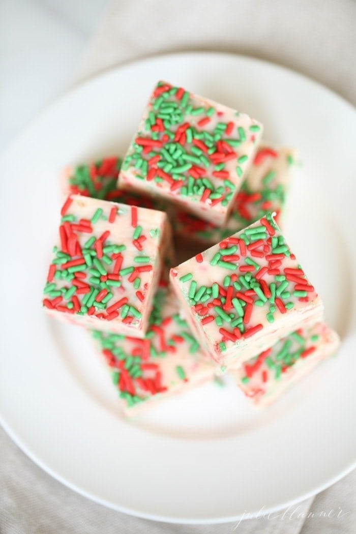 white fudge slices with christmas sprinkles on a white plate.