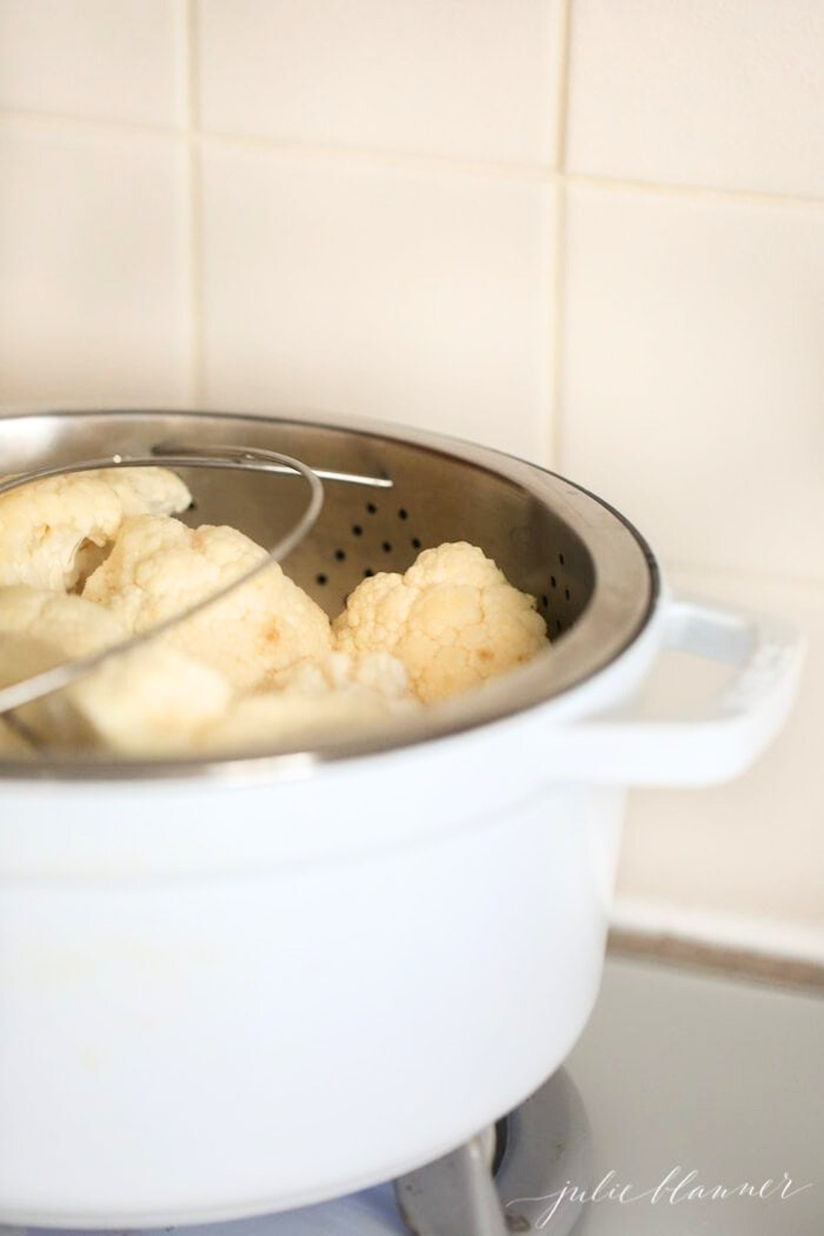 A white pot filled with cauliflower on top of a stove.