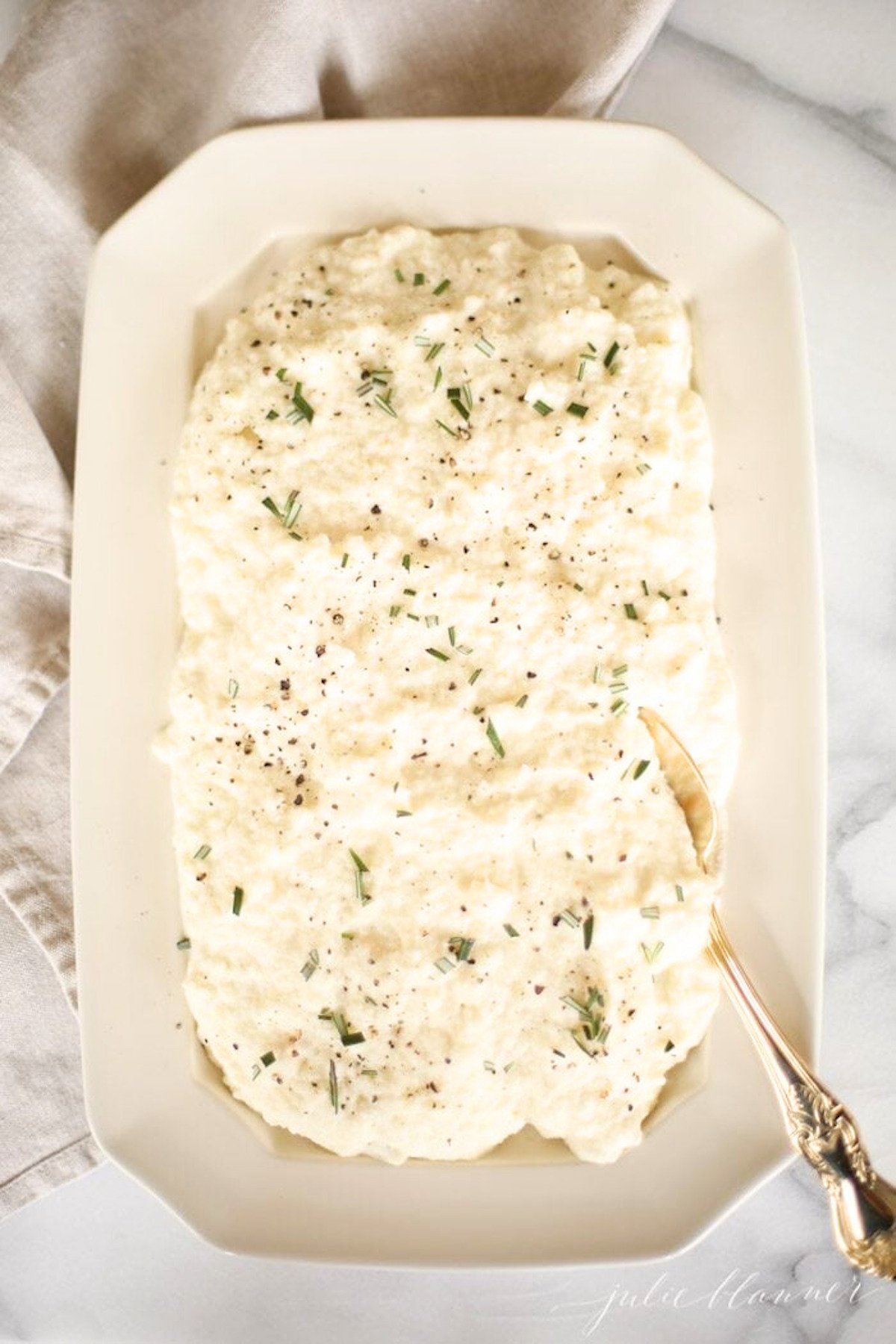 A white plate with mashed cauliflower on it.