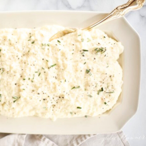 A white plate with mashed cauliflower on it.