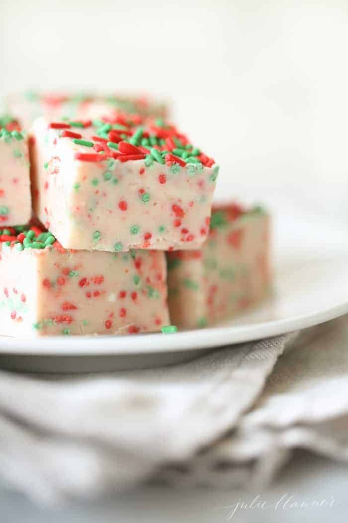 A stack of white chocolate fudge with Christmas sprinkles on a white plate.