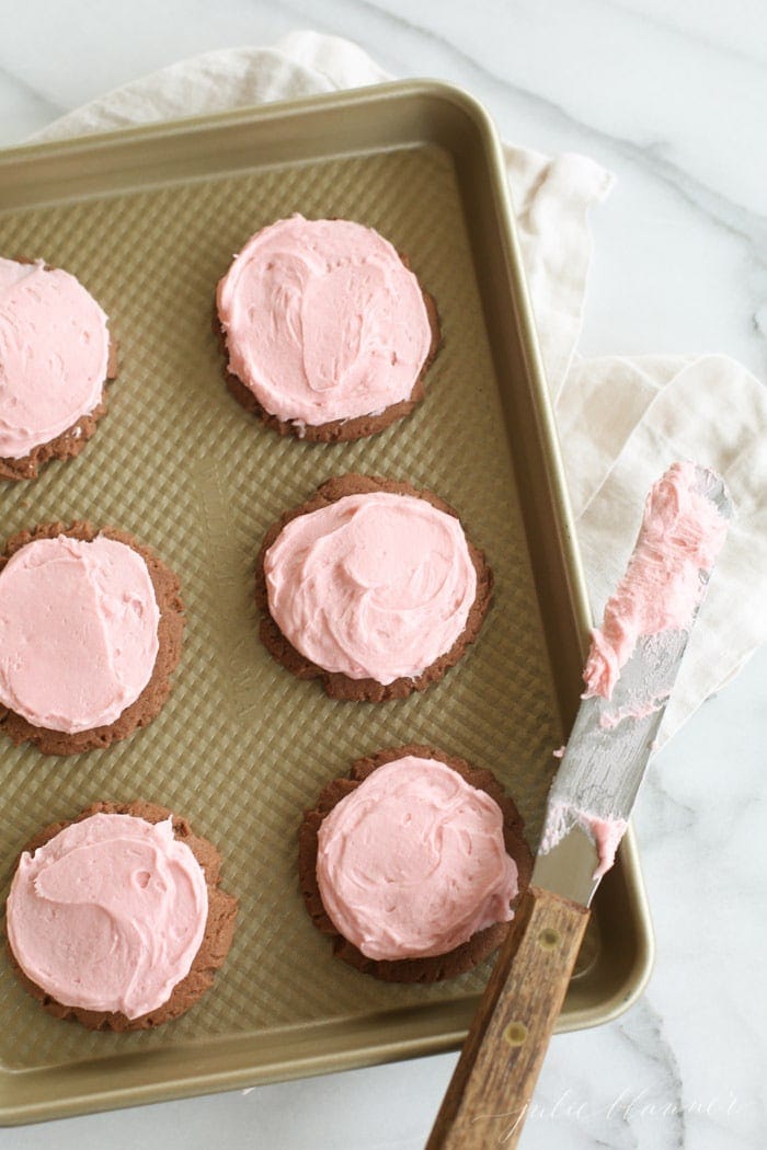 chocolate sugar cookies with buttercream icing on a baking sheet