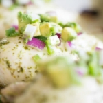 A baked chicken breast topped with pico de gallo with avocado.