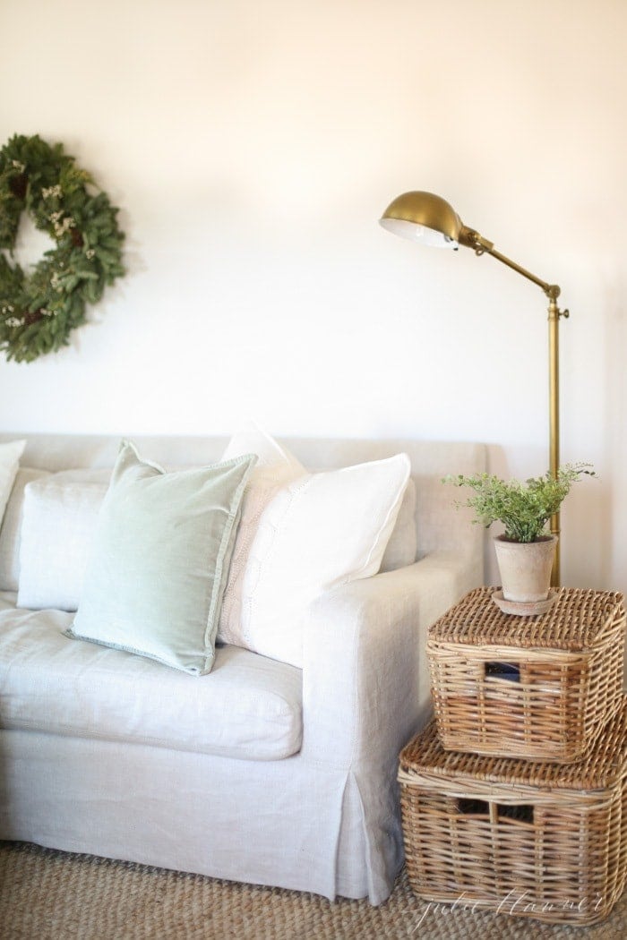 Winter decor of an evergreen wreath hung over a linen couch.