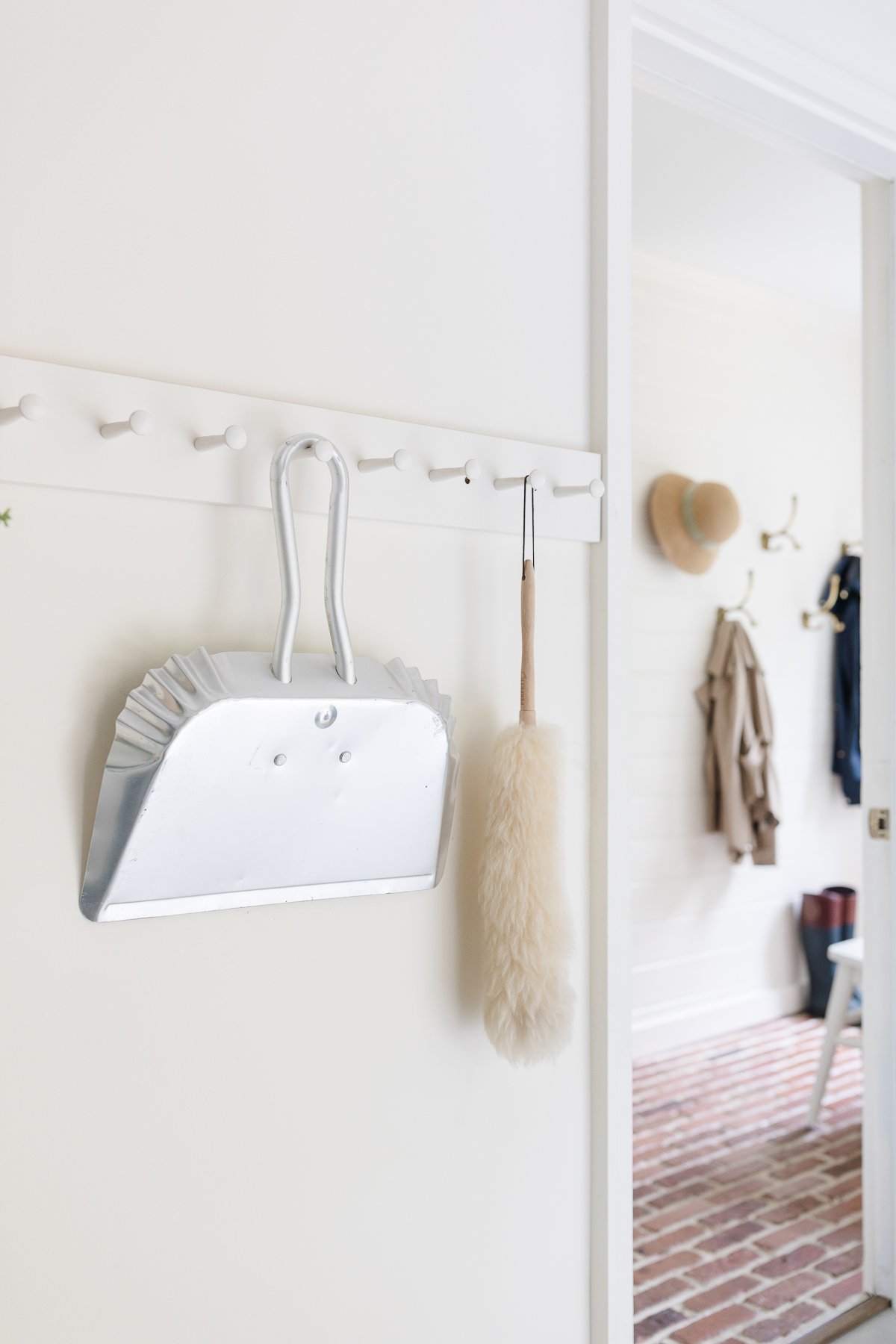 A mudroom with white walls and brick flooring.