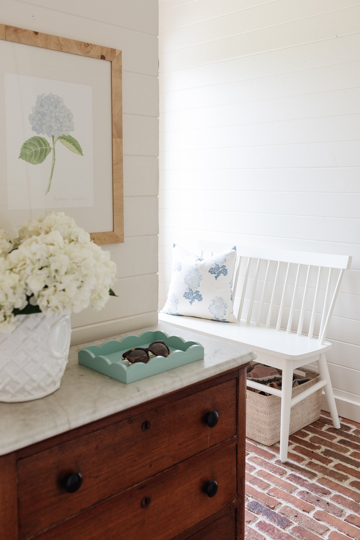 A mudroom with white wood paneled walls and brick flooring.