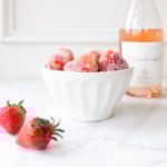 rosé marinated drunken strawberries in a white bowl, bottle of wine in the background.