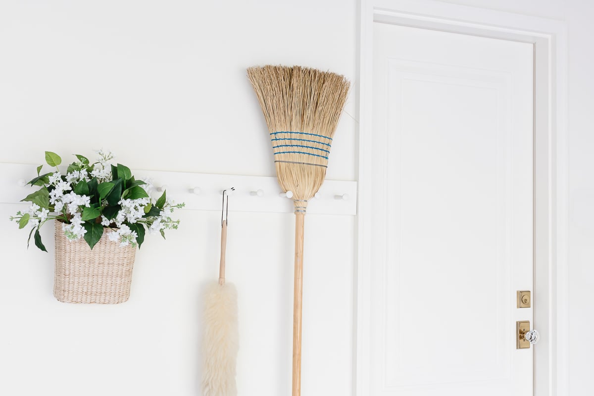 A white wall with peg rail holding clean supplies in a garage organization guide.