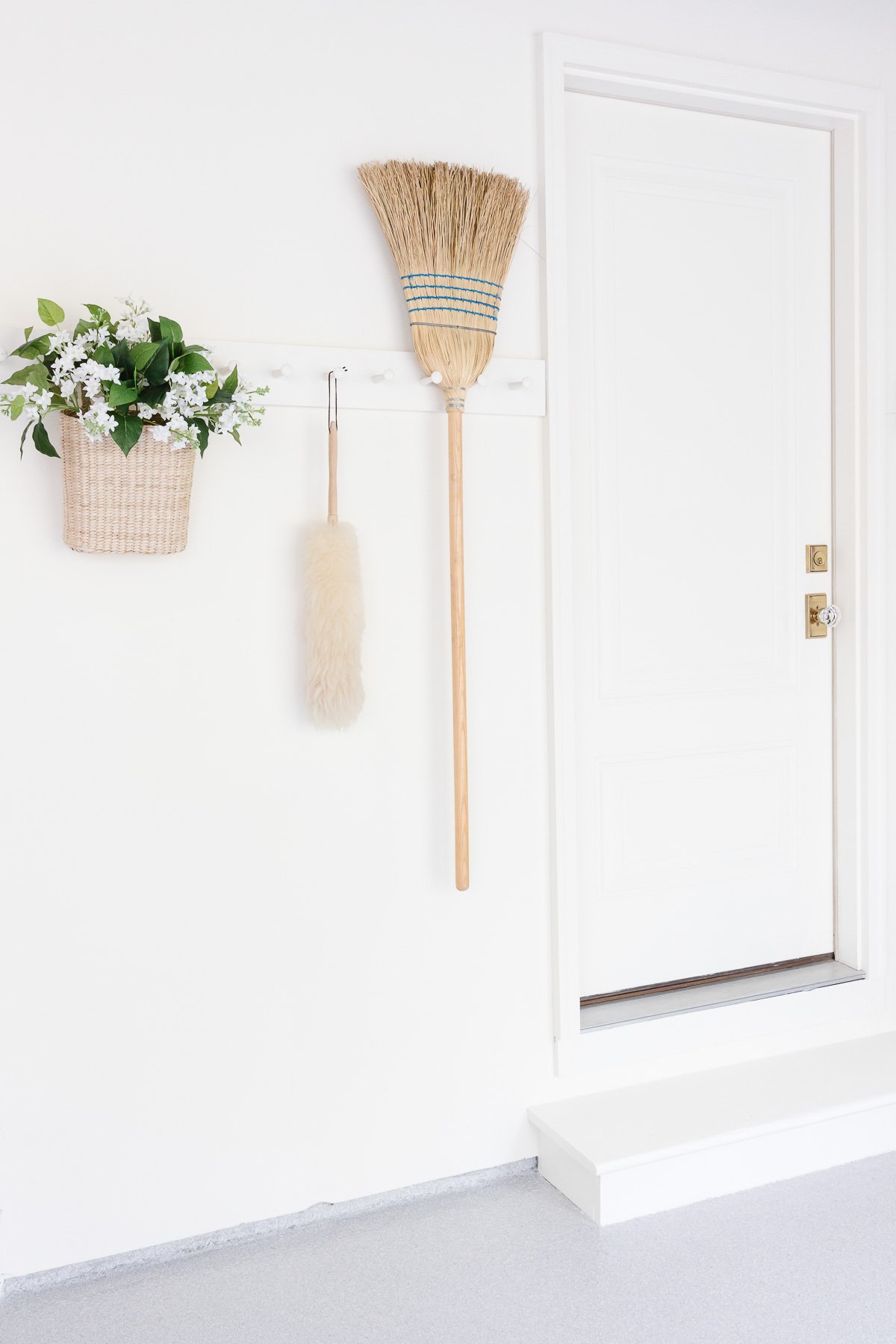 A white wall with peg rail holding clean supplies in a garage organization guide.