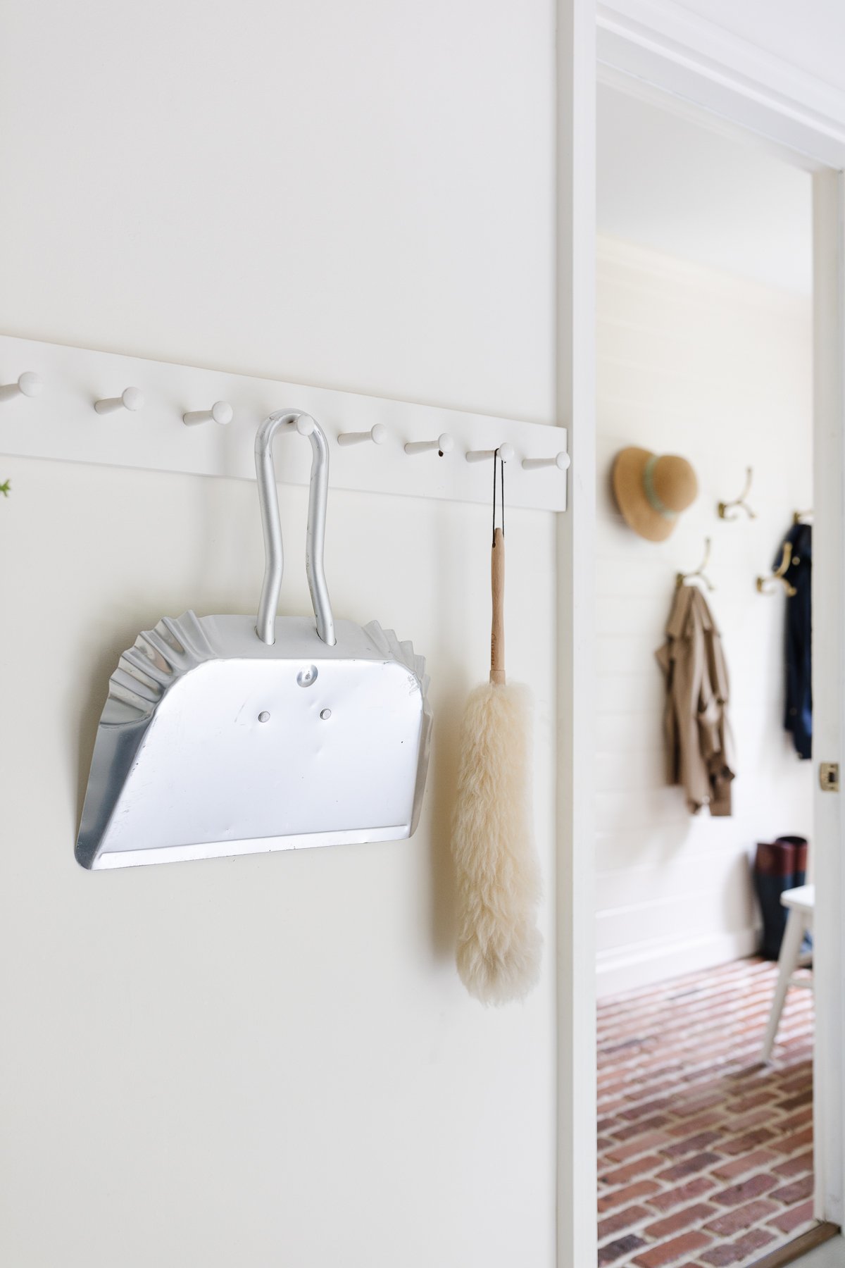 A white wall with peg rail holding clean supplies in a garage organization guide. 