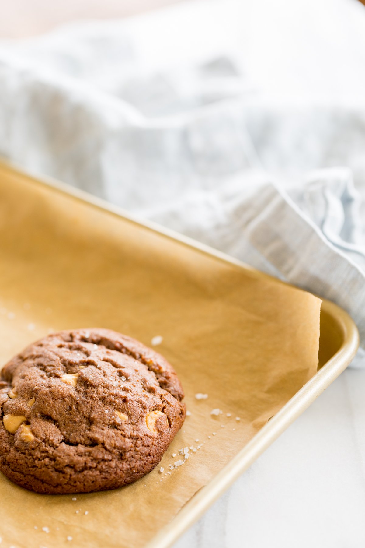 A gold baking tray lined with parchment, full of chocolate cookies with peanut butter chips.