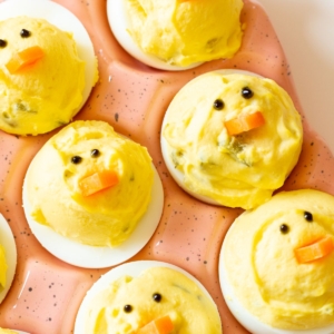 Deviled eggs made into little Easter chicks, on a pink ceramic egg holder.