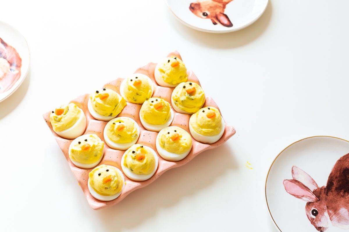 Deviled eggs made into little Easter chicks, on a pink ceramic egg holder.