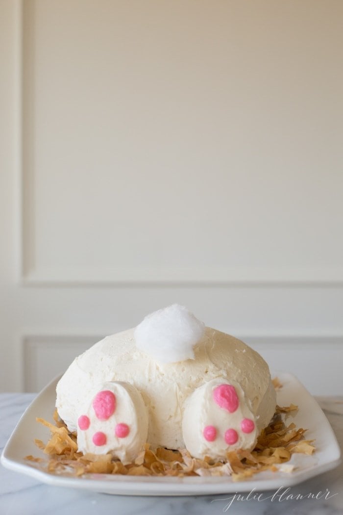 A vintage inspired bunny cake with a bunny tail made of cotton candy on a white platter.