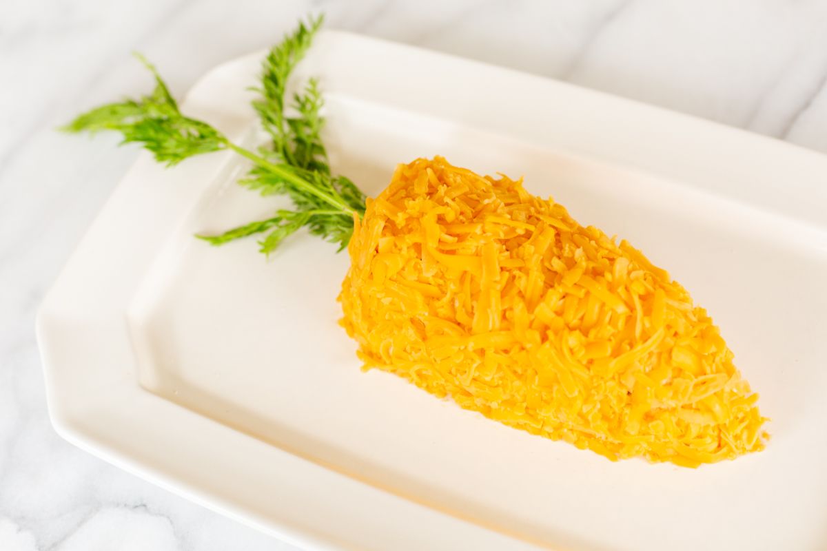 A carrot cheese ball on a white platter.