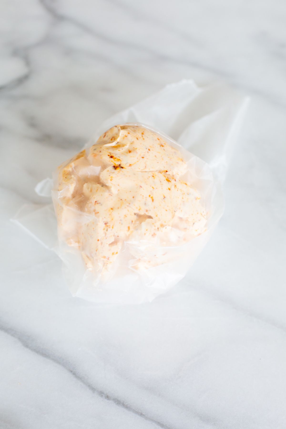 A cheese ball formed into a round ball, in between layers of wax paper.