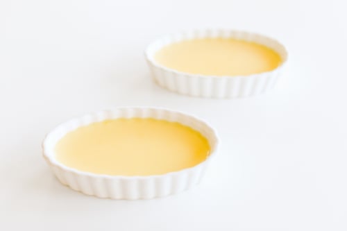 Two bowls of easy creme brulee on a white surface.