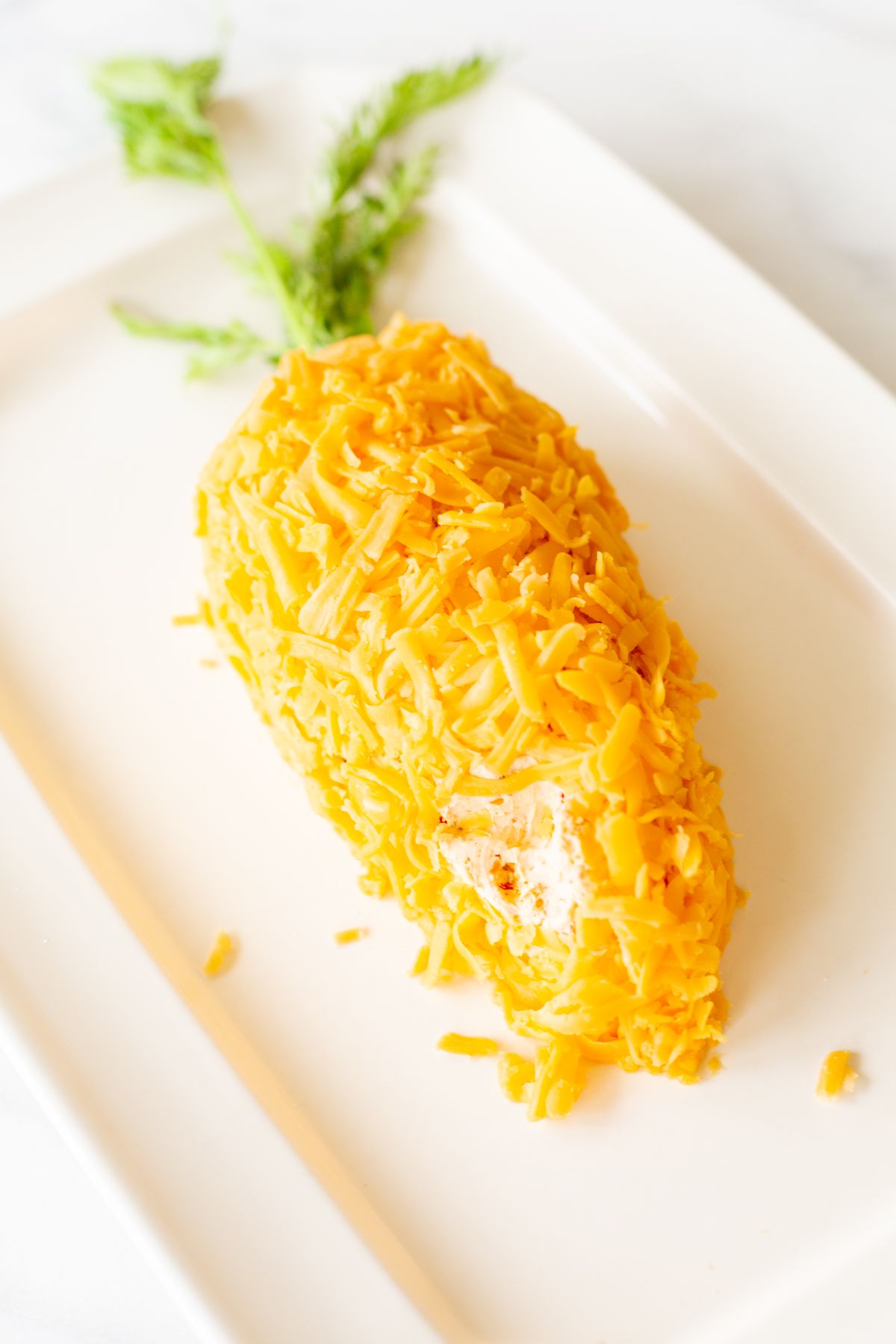 A carrot cheese ball on a white platter.