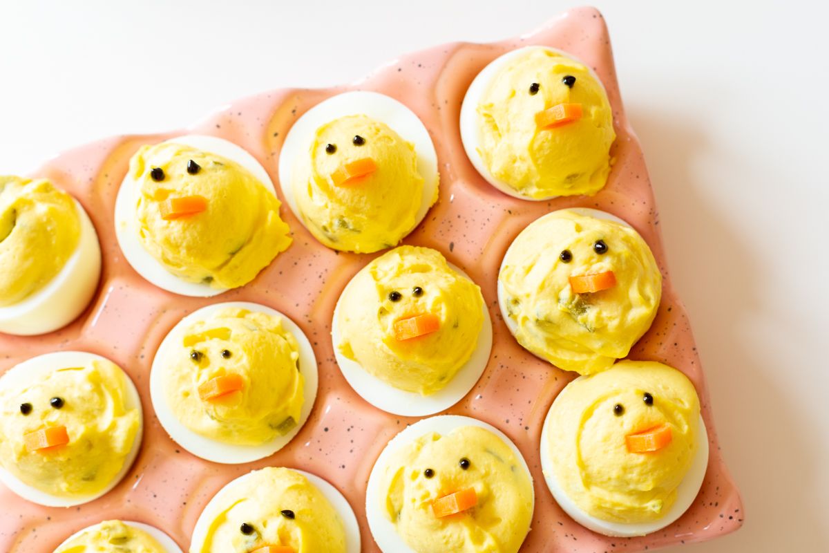 Deviled eggs made into little Easter chicks, on a pink ceramic egg holder.