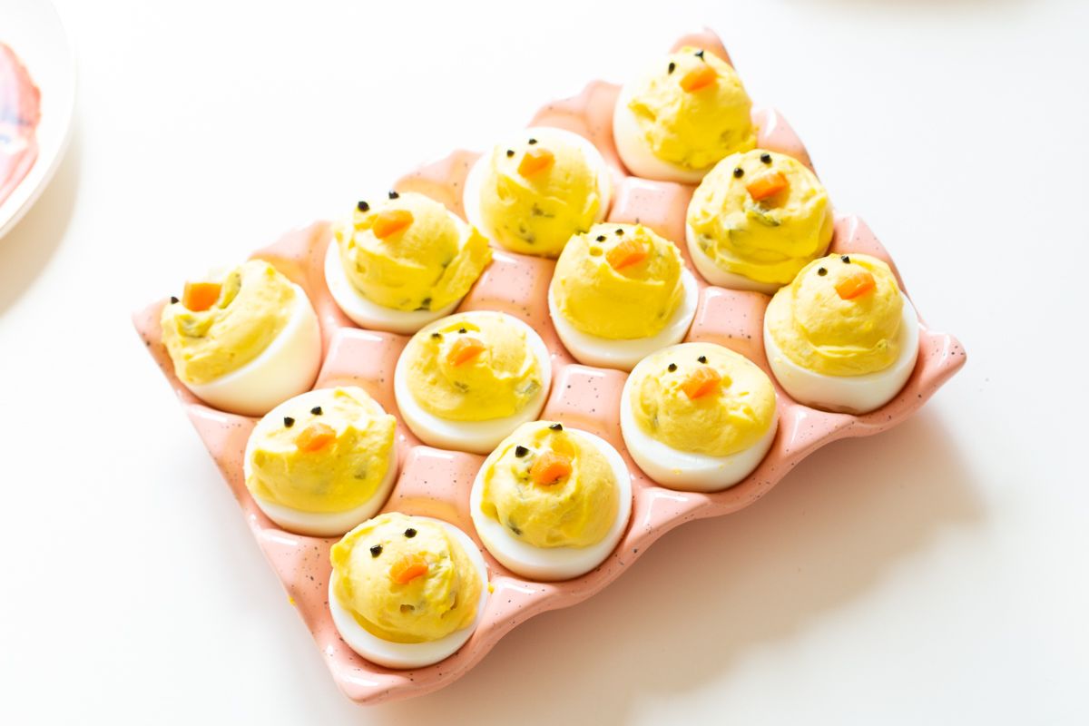 Deviled eggs made into little Easter chicks, on a pink ceramic egg holder.