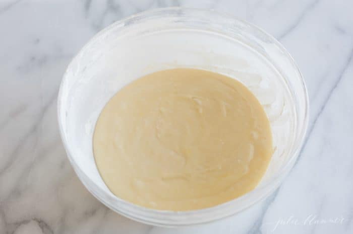 A clear glass pyrex mixing bowl filled with cake mix on a marble surface.