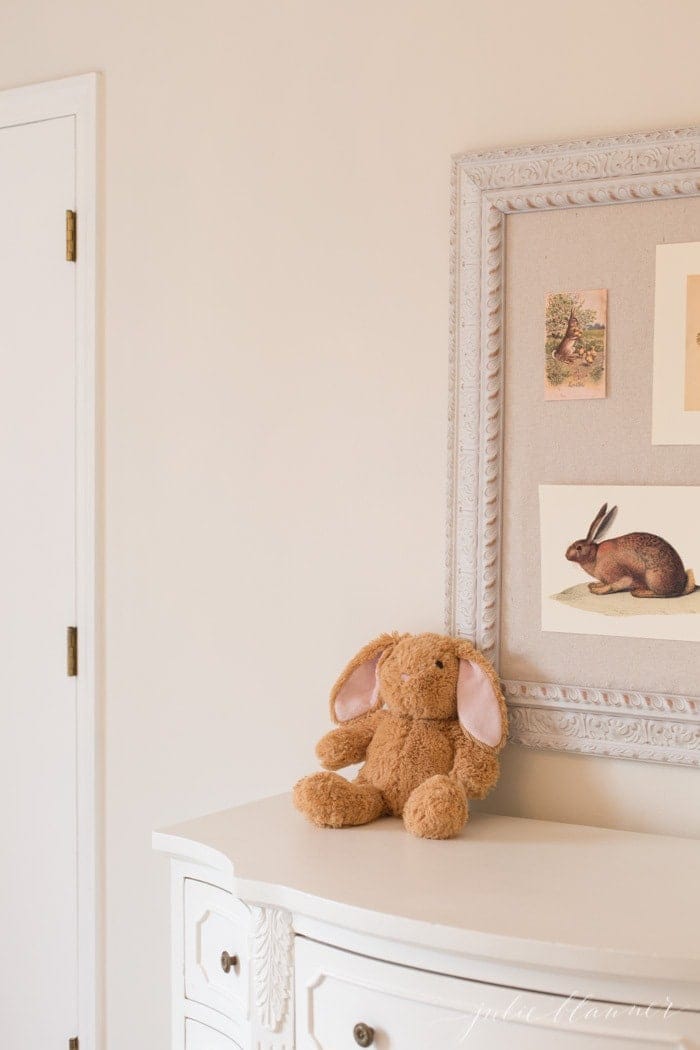 A girl's dresser in a white bedroom, Easter decorating ideas on the pinboard.