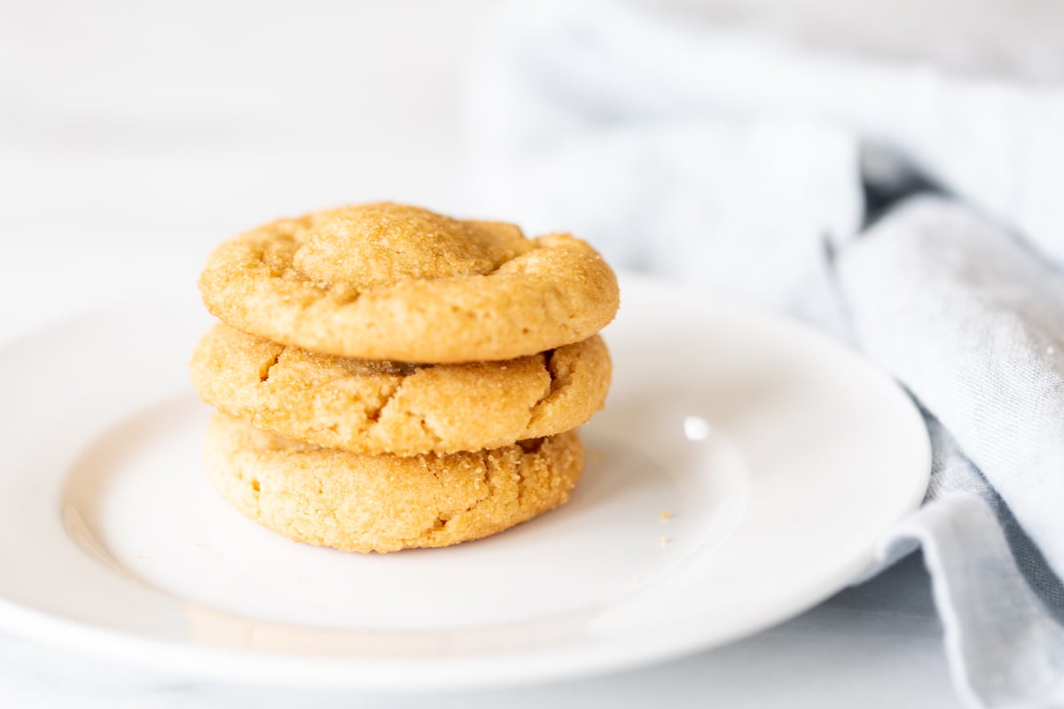 A white plate with a stack of three chocolate stuffed peanut butter cookies.