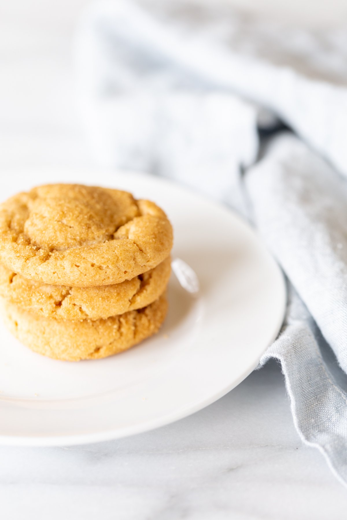 A white plate with a stack of three chocolate stuffed peanut butter cookies.