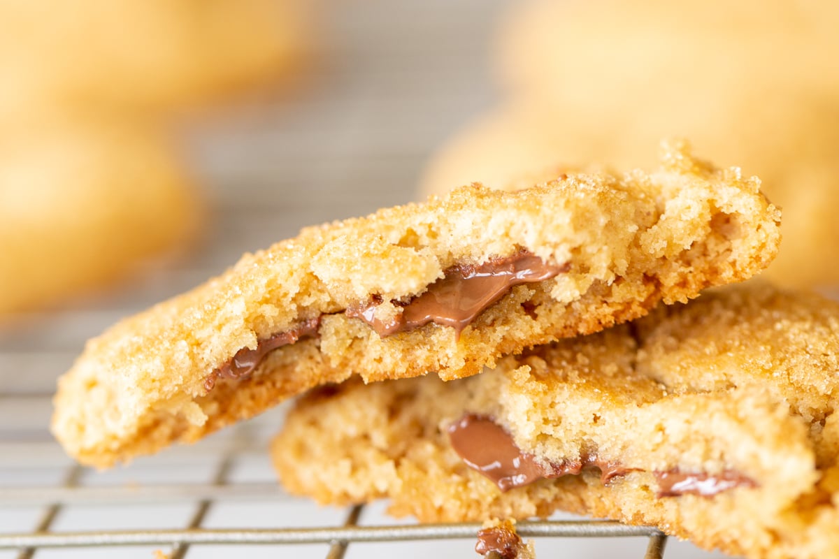 A cooling rack with a chocolate stuffed peanut butter cookie split into two halves.