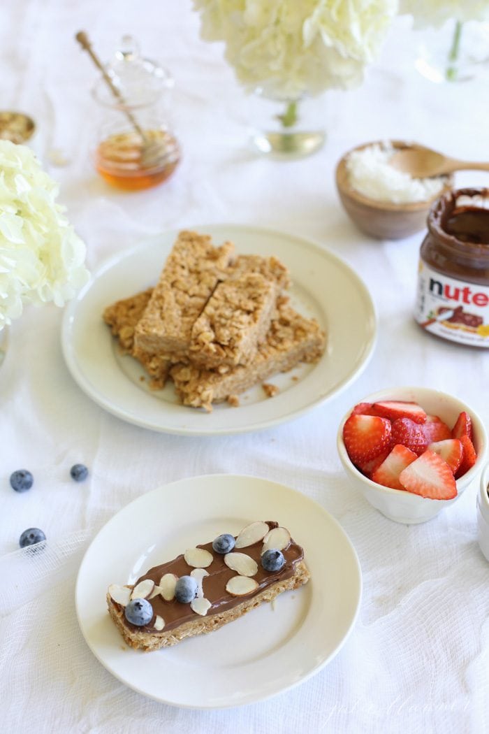 Peanut butter granola bars next to bowls of different toppings