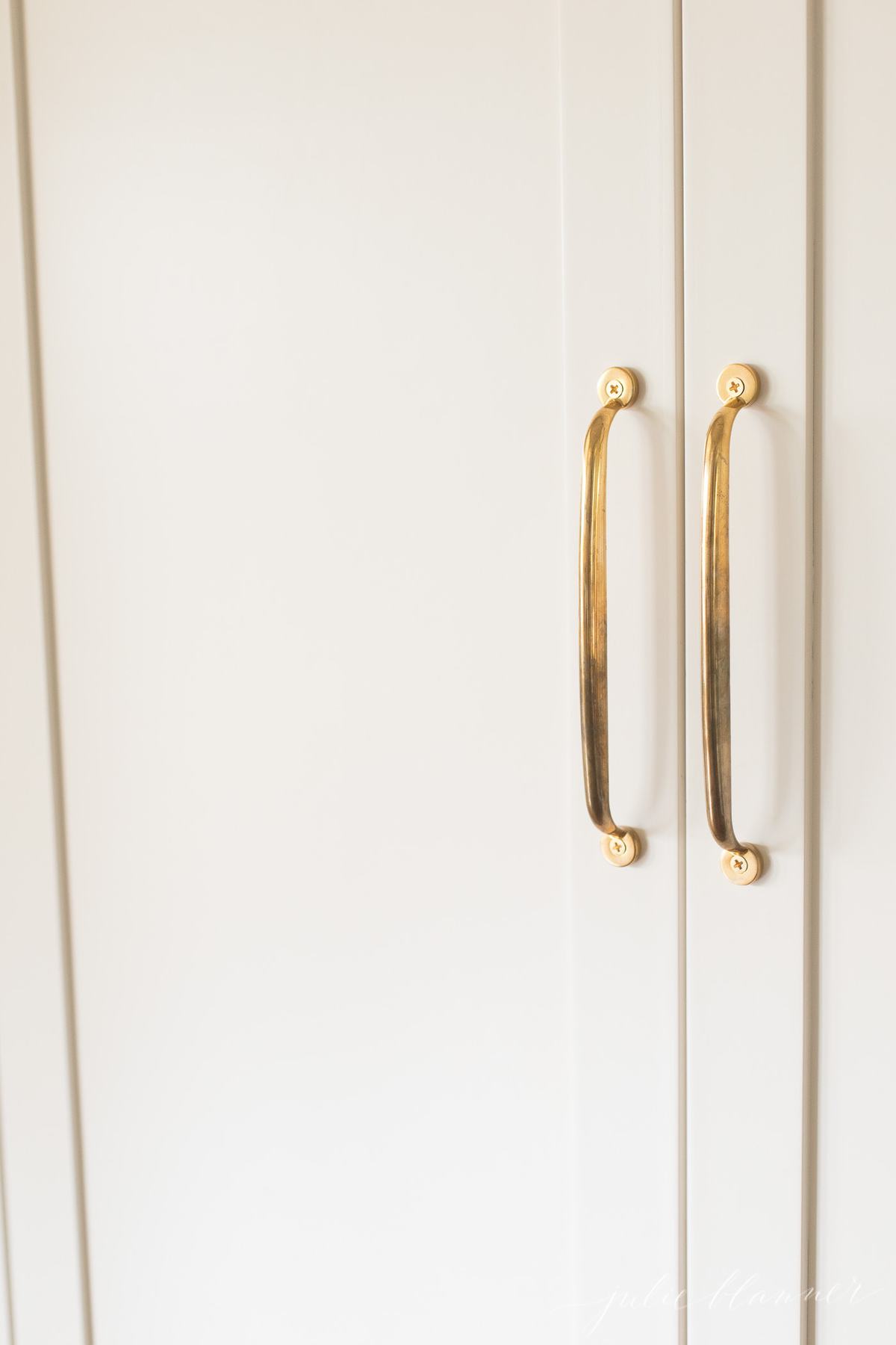 unlacquered brass appliance pulls on a paneled refrigerator.